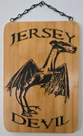 a wooden sign with a bat-like creature and the text "JERSEY DEVIL" printed on it.