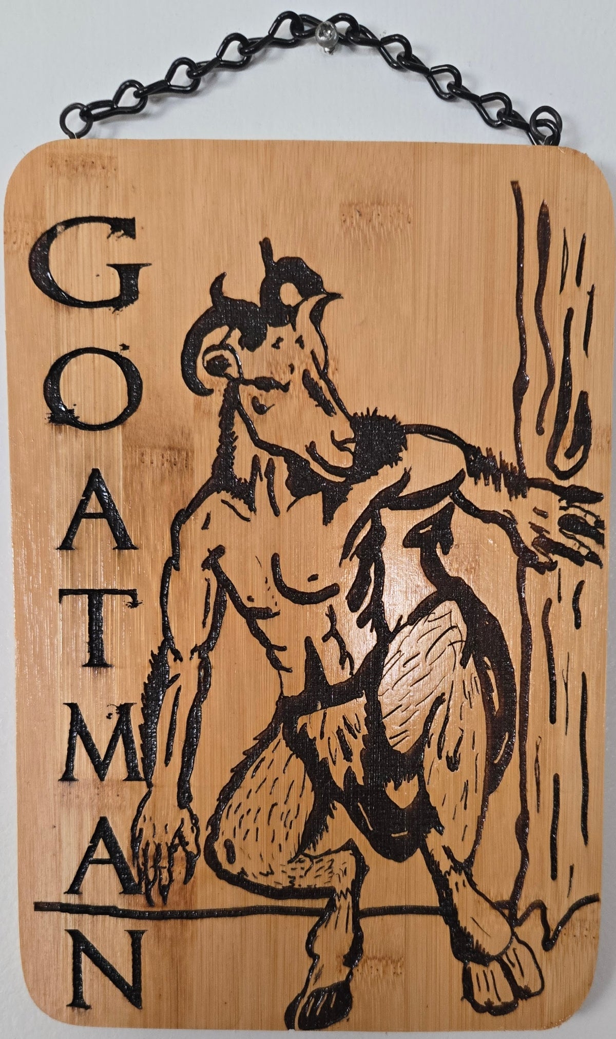 a wooden sign with a black and white illustration of a goat-like creature, possibly a mythical or fantastical animal, and the word "Goat" written on it.