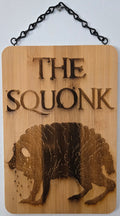 a wooden plaque with the text "THE SQUONK" and an illustration of a bear.